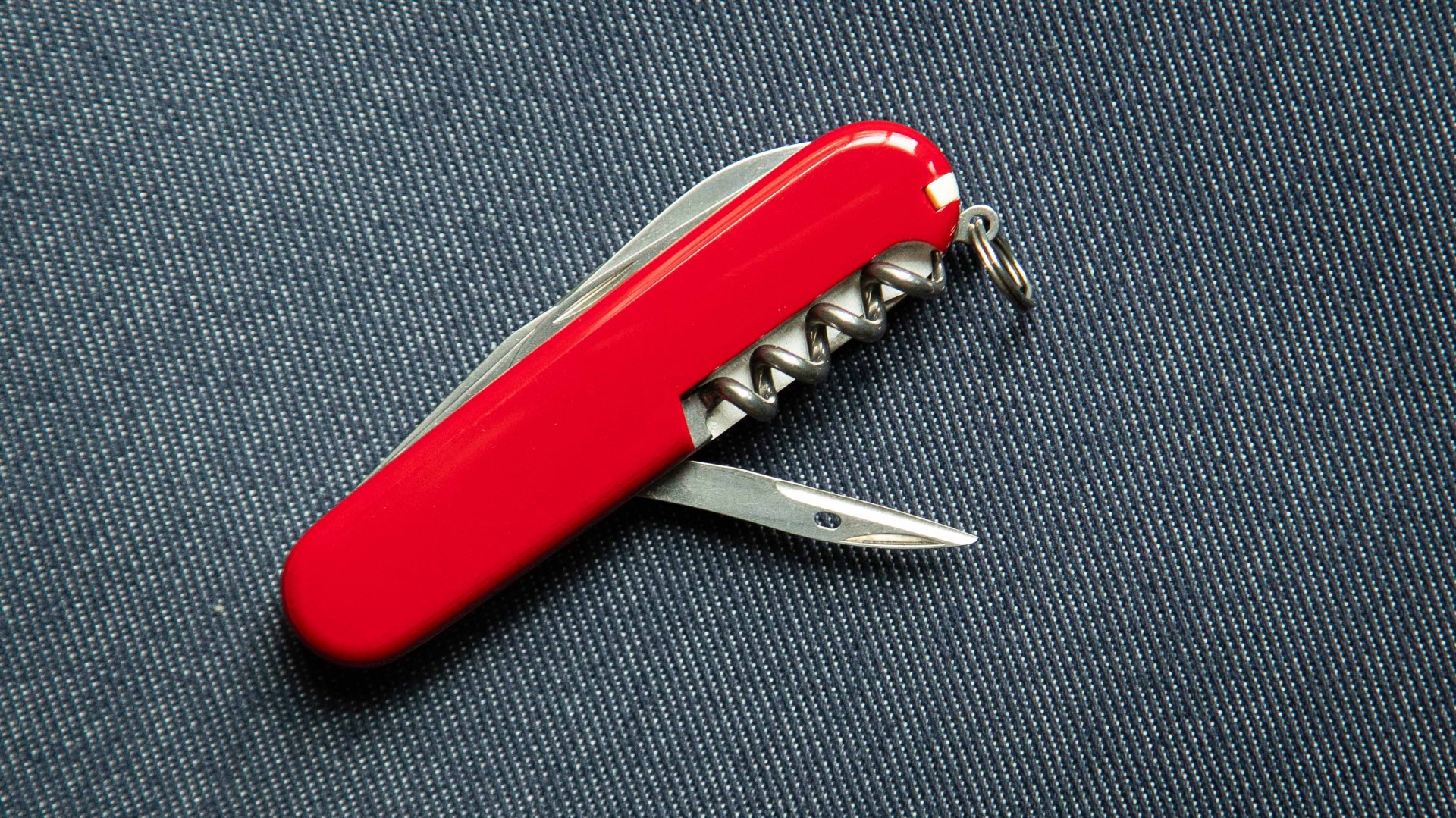 red swiss army knife on blue denim background