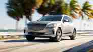 Genesis GV80 driving in front of palm trees