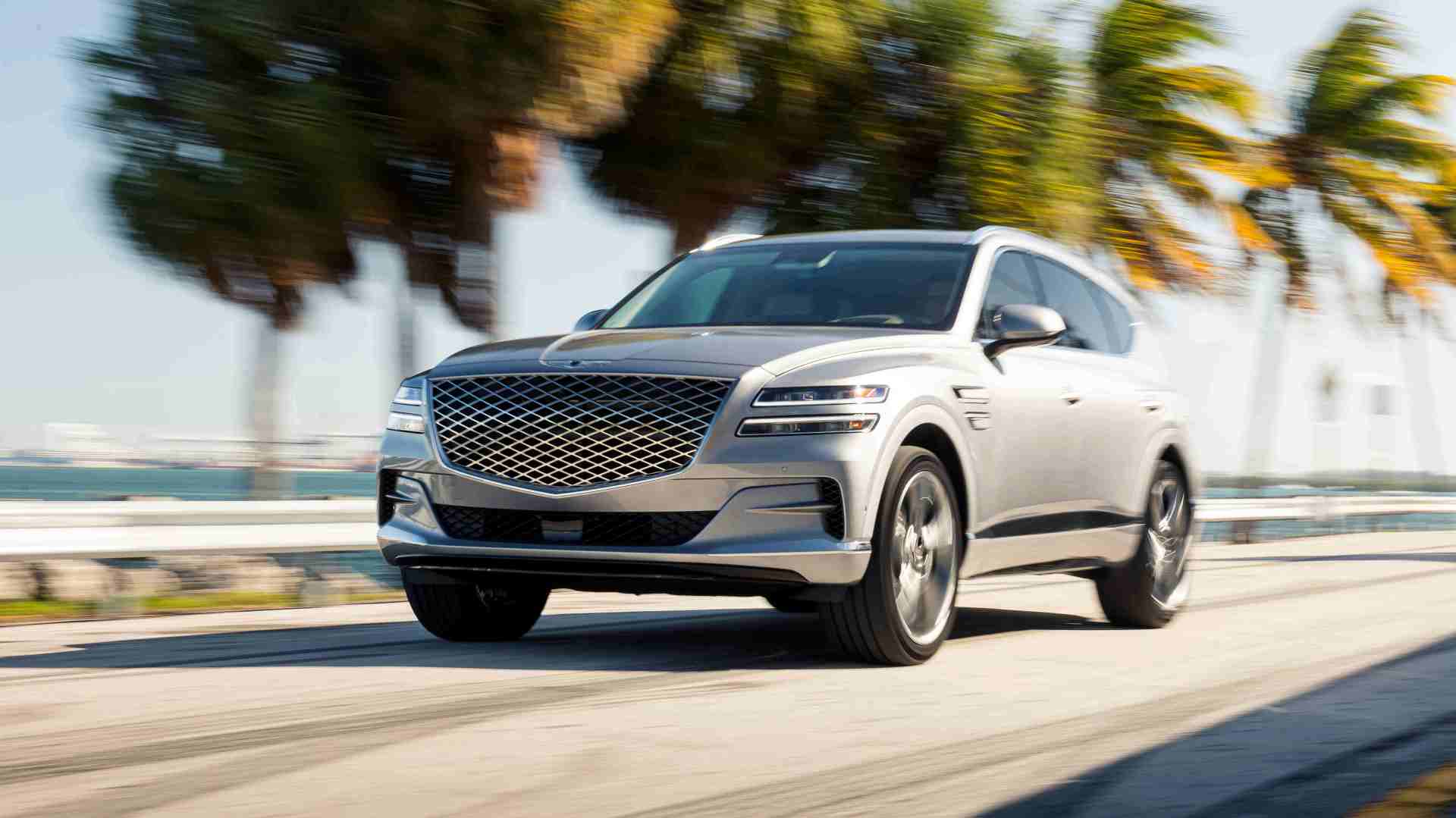 Genesis GV80 driving in front of palm trees