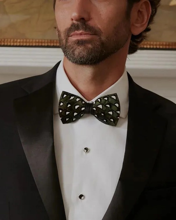 a man wearing a suit and brackish feather bow tie