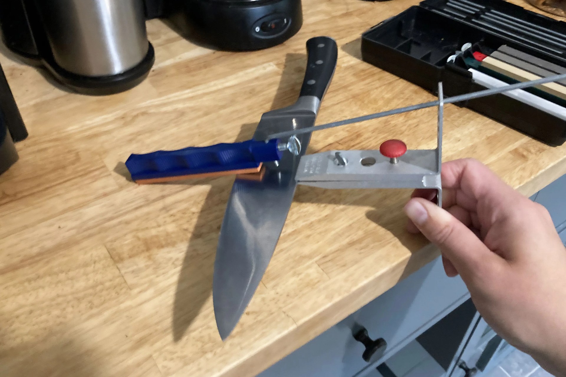 a person holding a knife sharpening system on a table