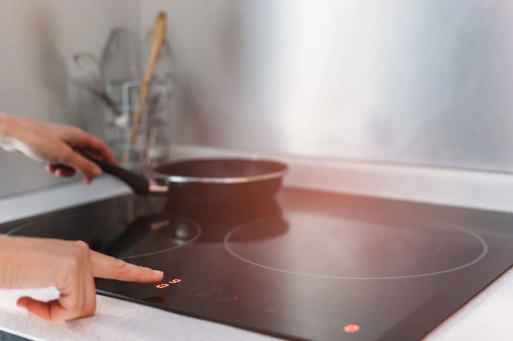 detail of female hand using induction stove in kitchen