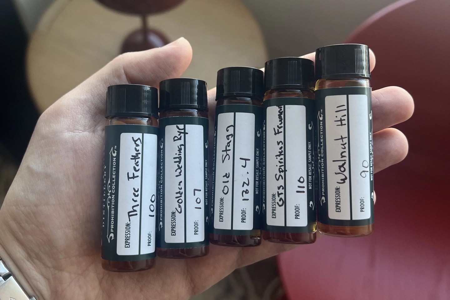 a hand holding a group of buffalo trace whiskey samples