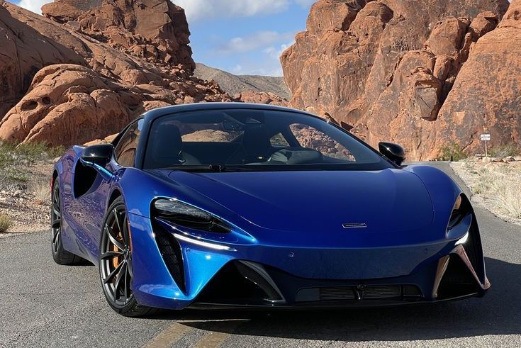 a blue sports car parked in front of a rocky cliff