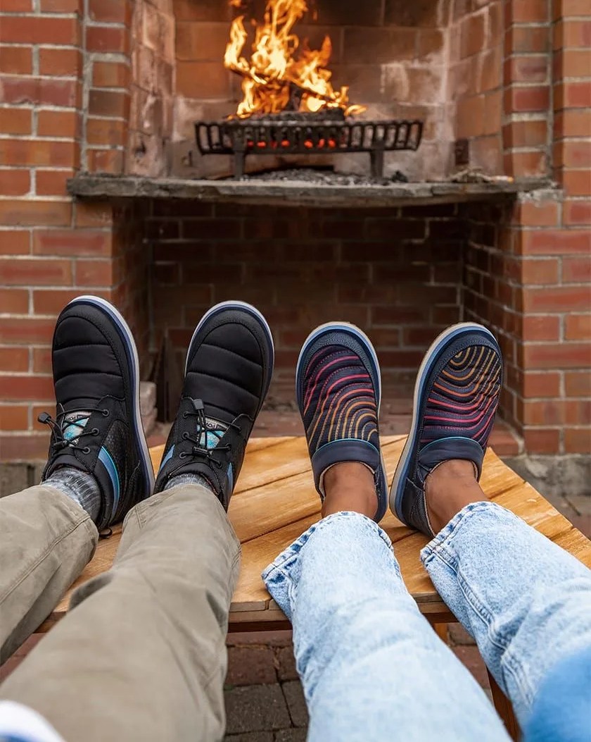 two people sitting in front of a fireplace