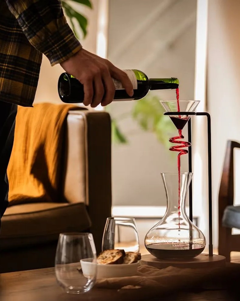 a person pouring a glass of wine into helical wine decanter set