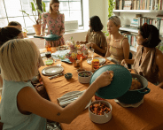 a group of women sitting around a table with food