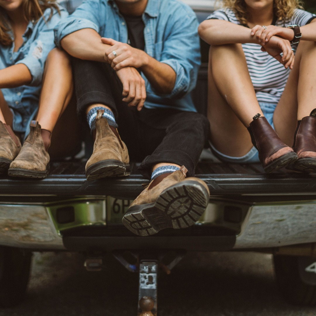 a group of people sitting on a truck in blundstone boots
