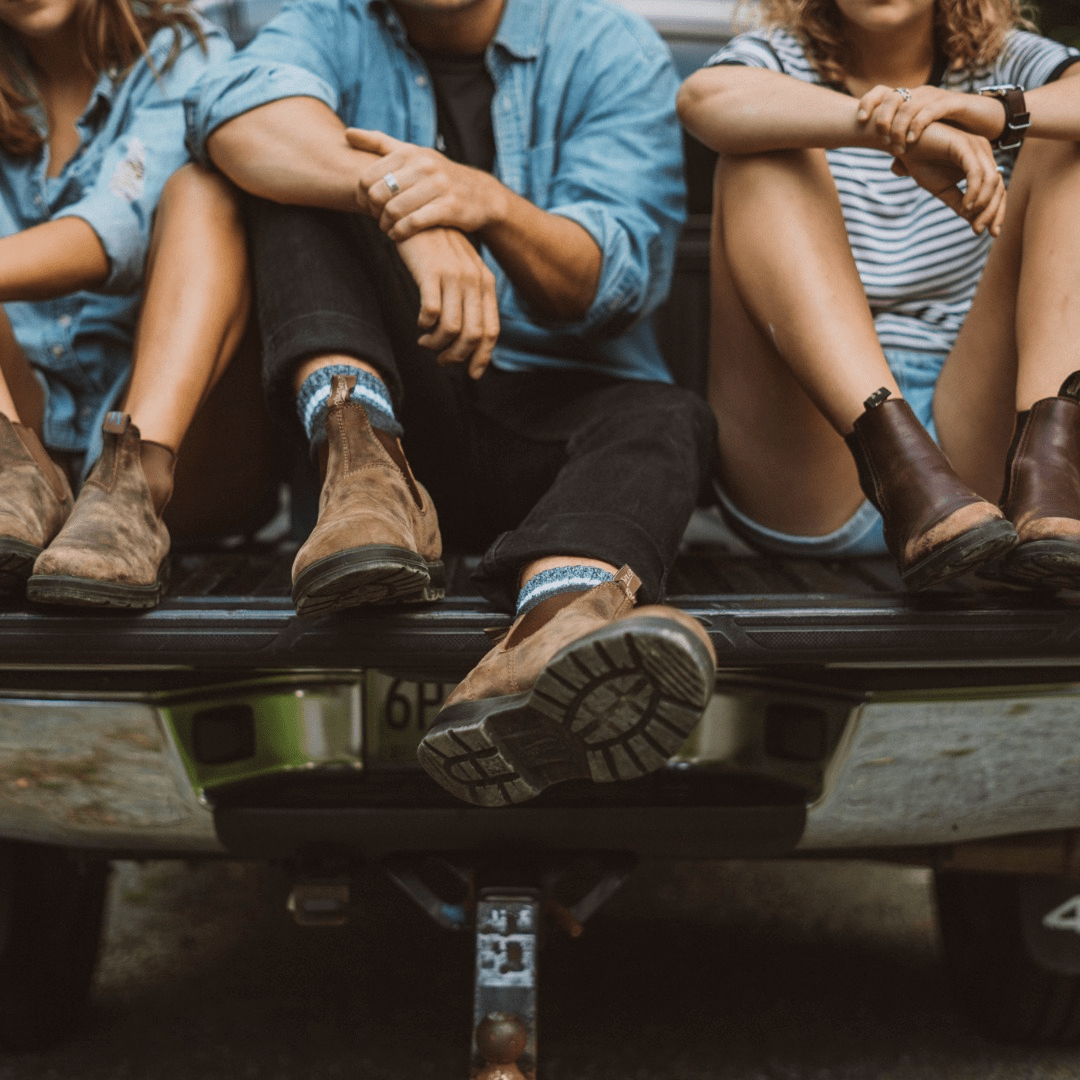 a group of people sitting on a truck in blundstone boots