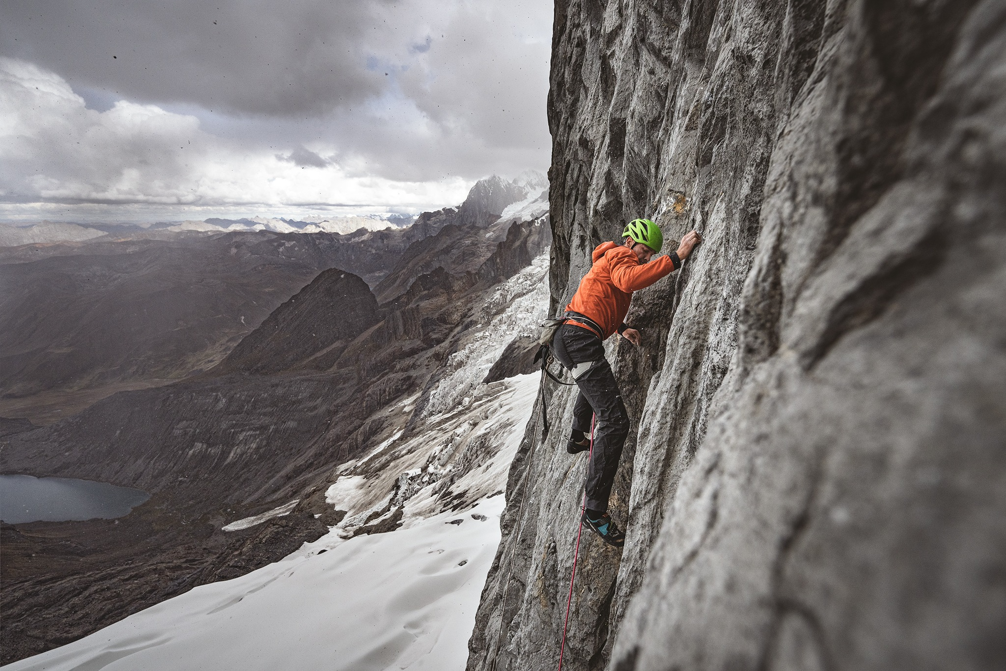 man in patagonia gear climbing a rock wall outdoors in winter