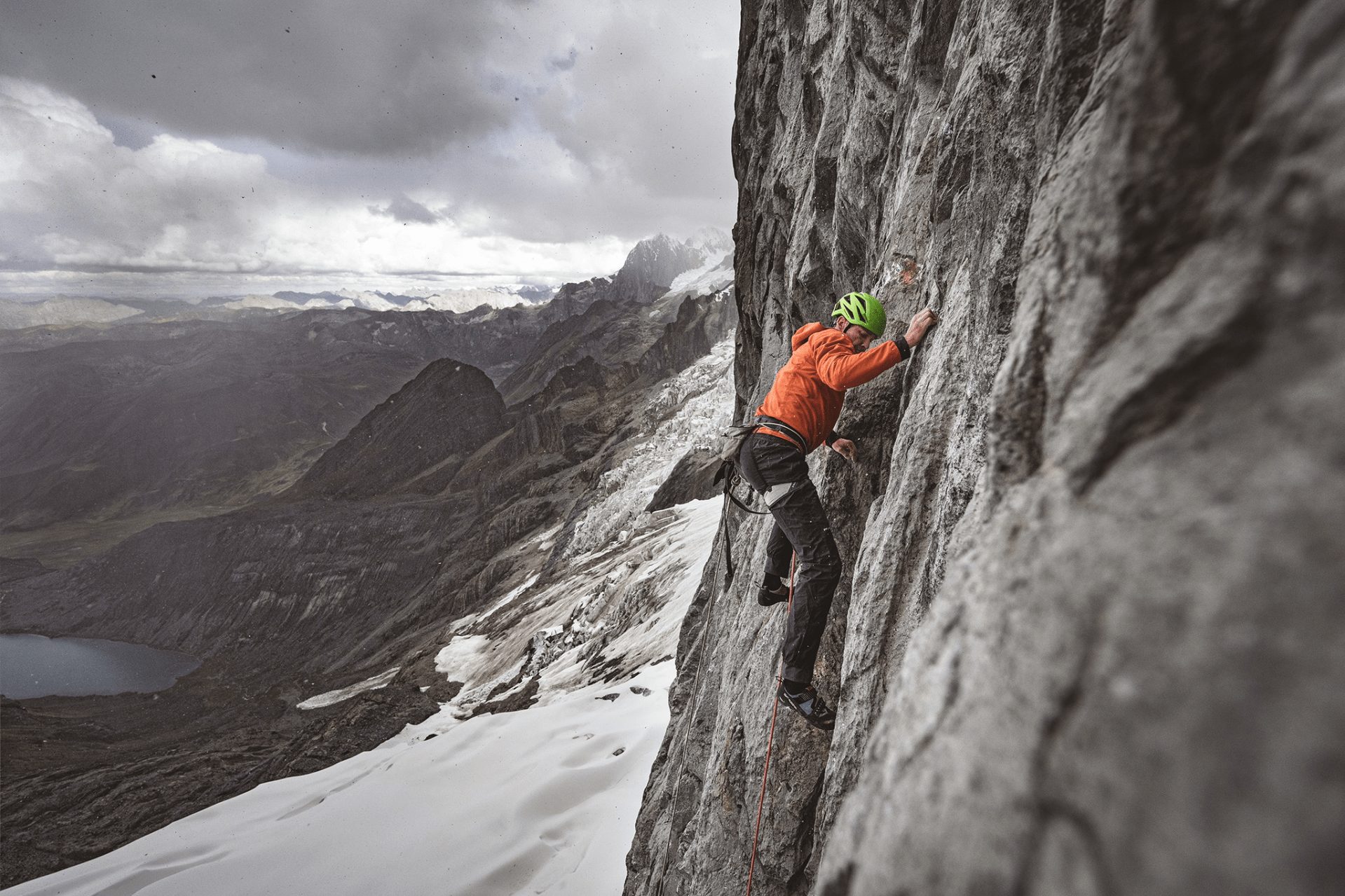 man in patagonia gear climbing a rock wall outdoors in winter