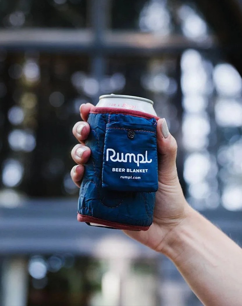 a person holding a can with rumpl beer blanket in deepwater