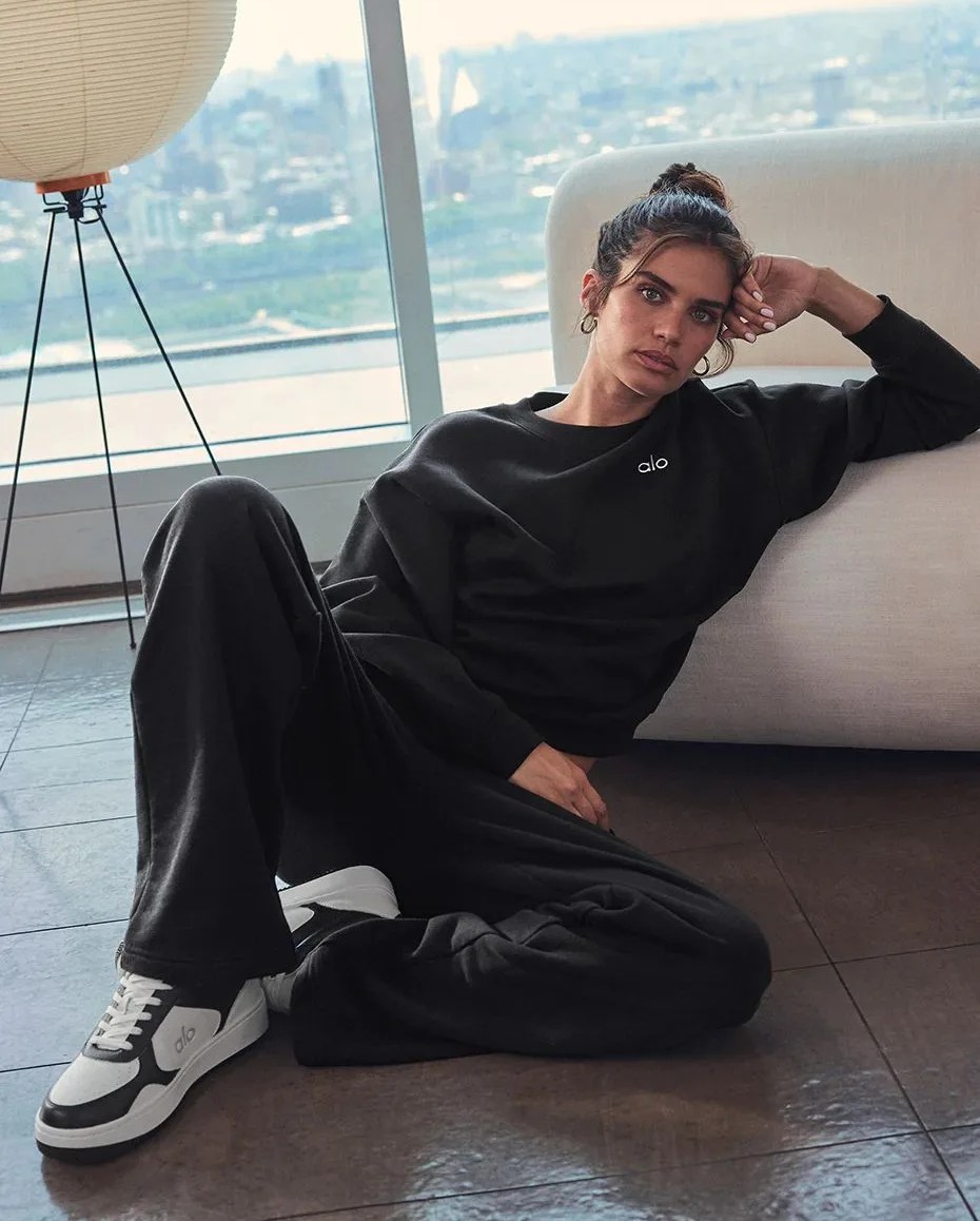 a person sitting on the floor wearing alo yoga sneakers