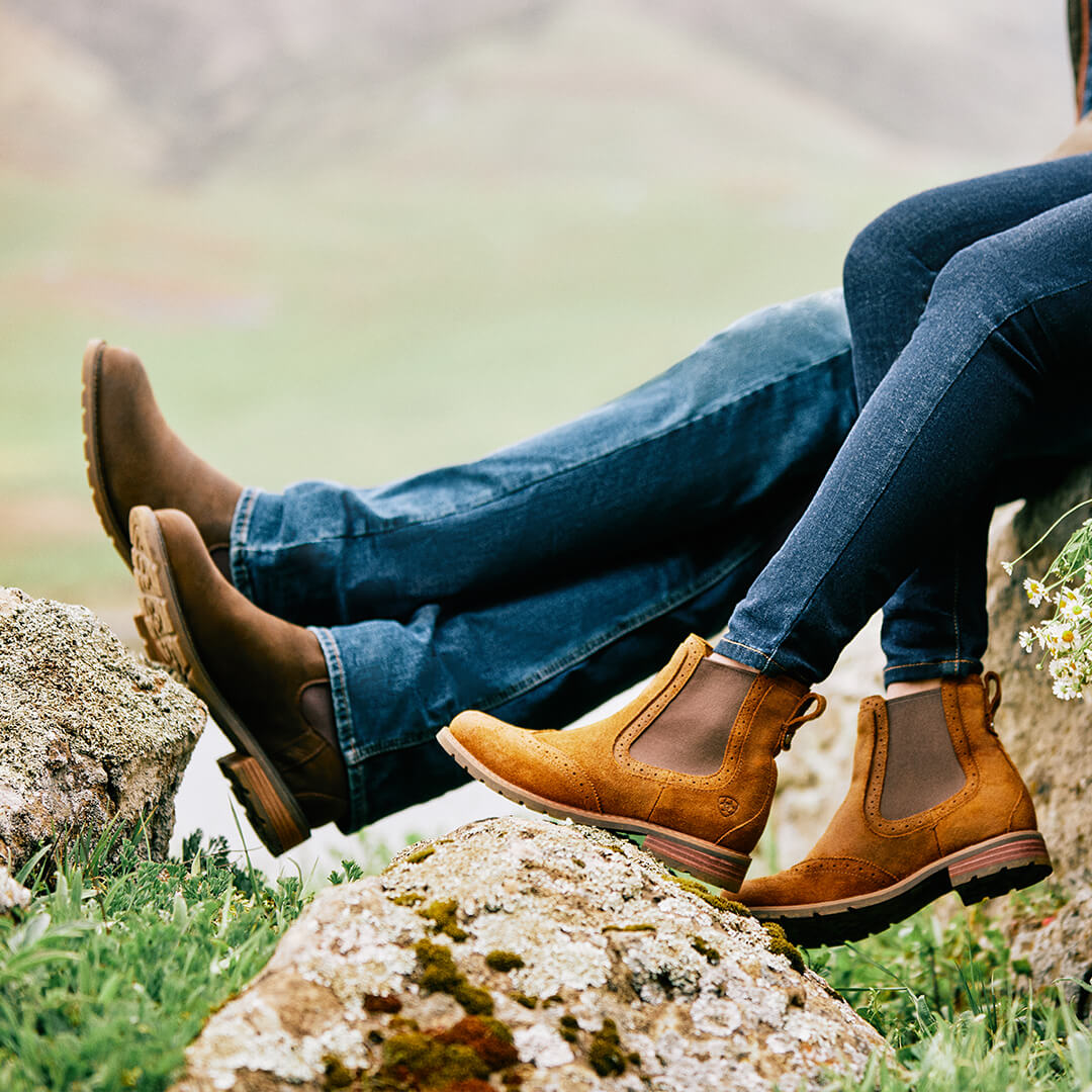 a person's legs and shoes on a rock