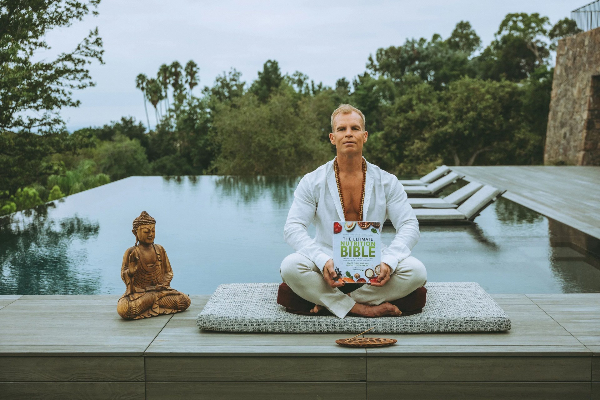 a person sitting on a stone platform holding bioptimizers book next to a statue