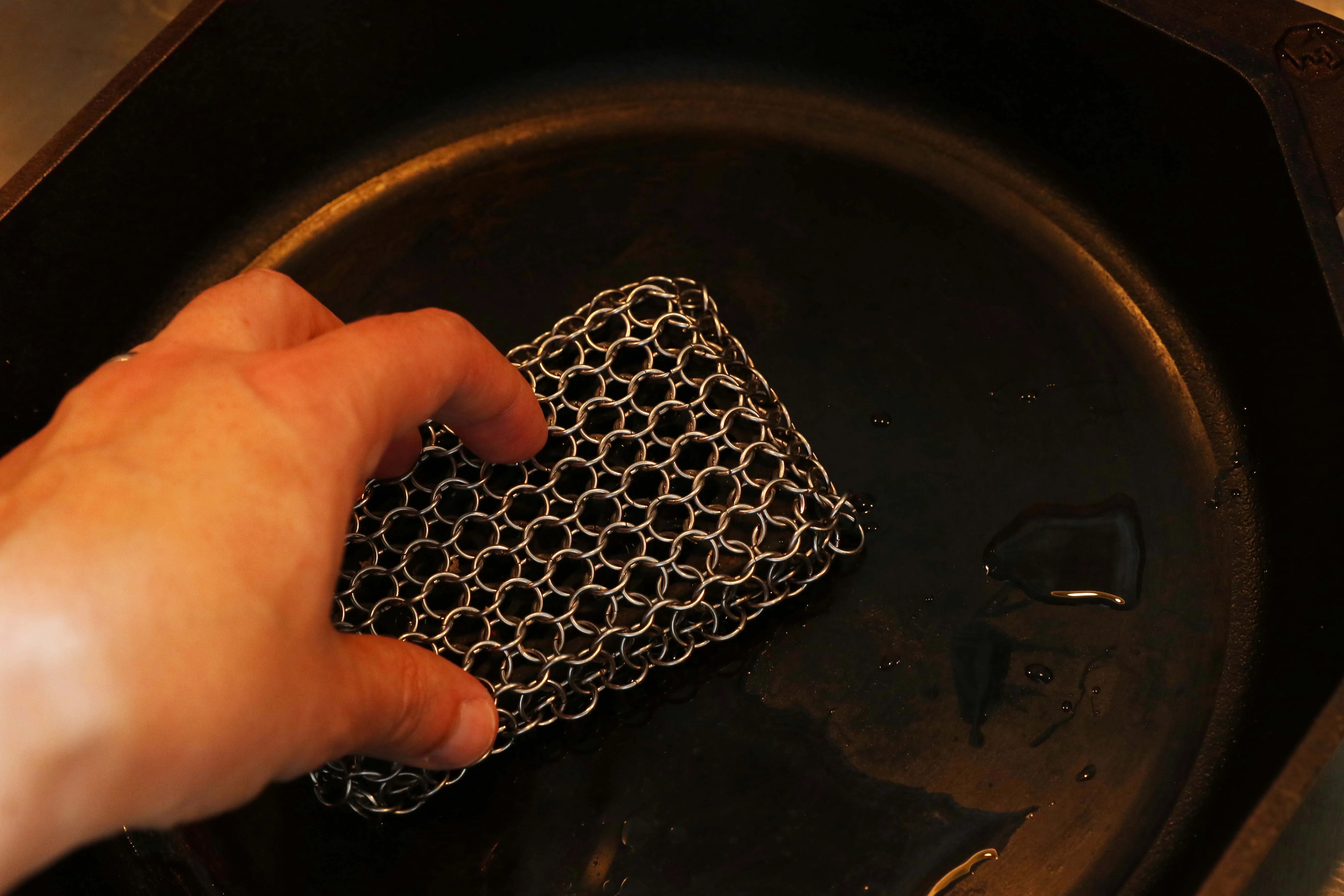 cleaning a cast iron skillet with a chainmail scrubber