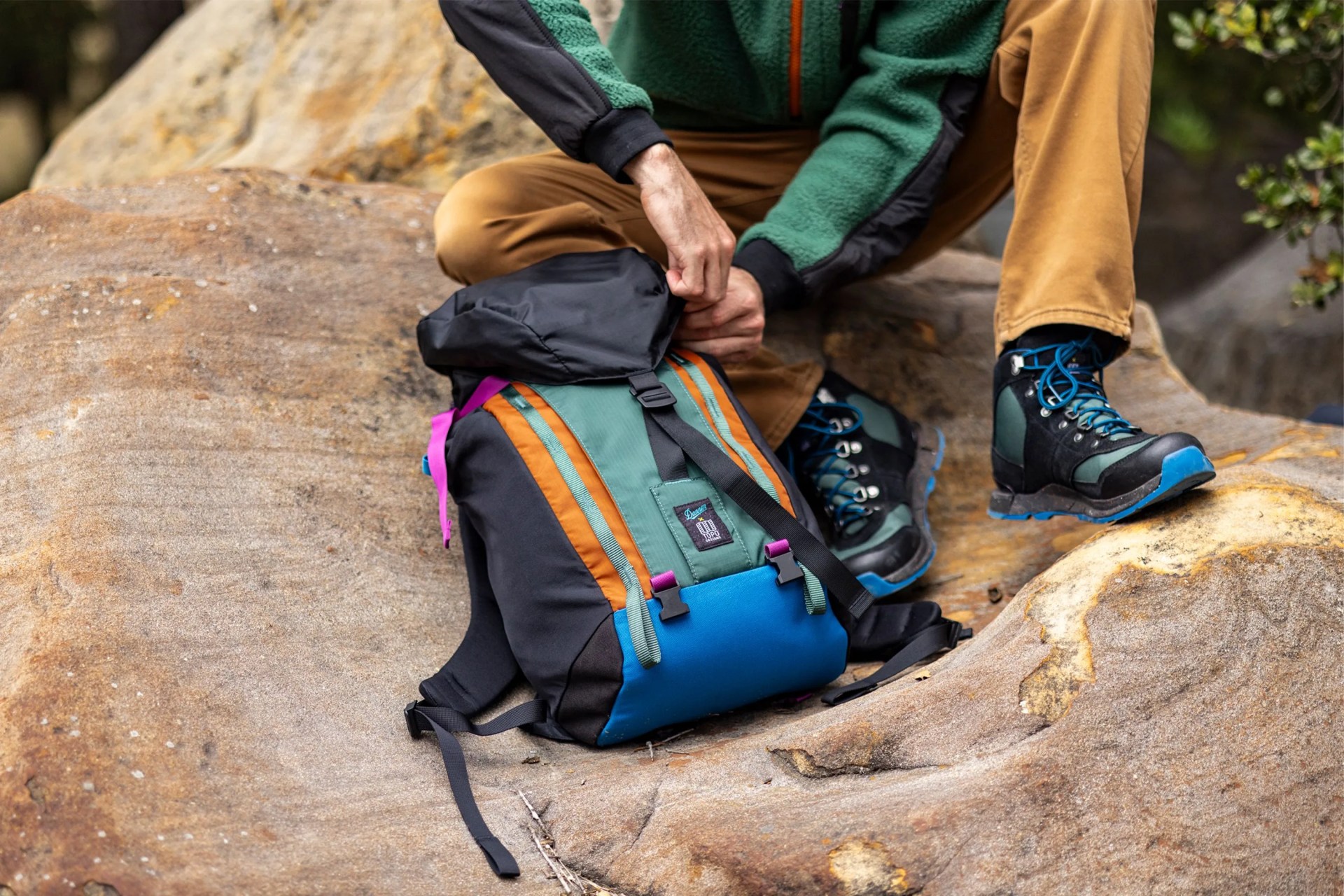 a person sitting on a rock with a backpack