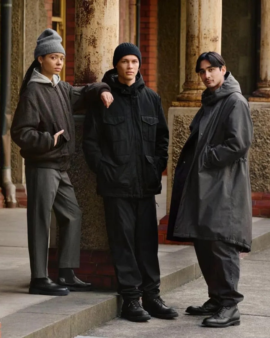 a group of men and women standing on the side of the street wearing uniqlo