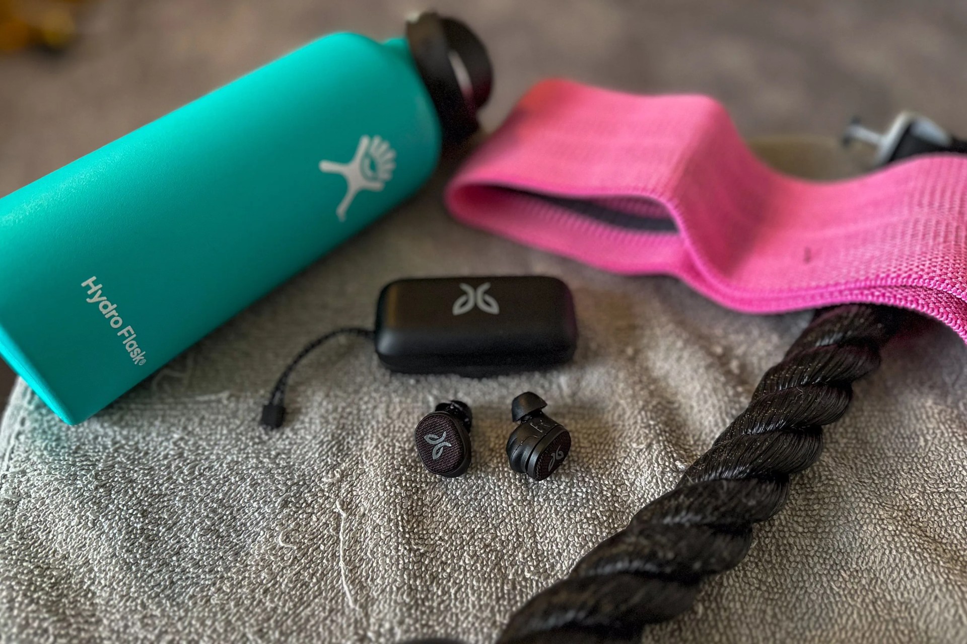 a bottle, ear buds, and workout gear on a towel