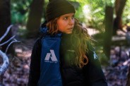 a woman in a sleeping bag and beanie in the woods