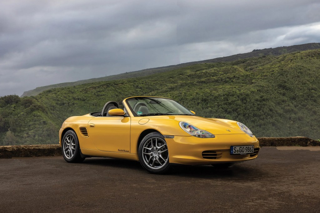 a yellow porsche boxter parked on a mountain