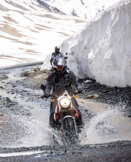 people riding motorcycles through watery dirt roads