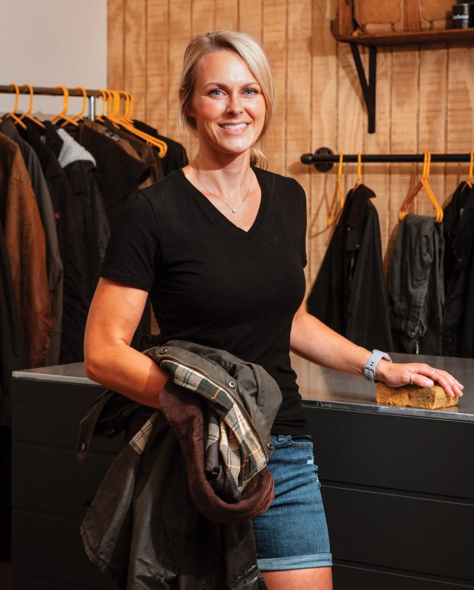 a woman standing in a workshop holding a jacket