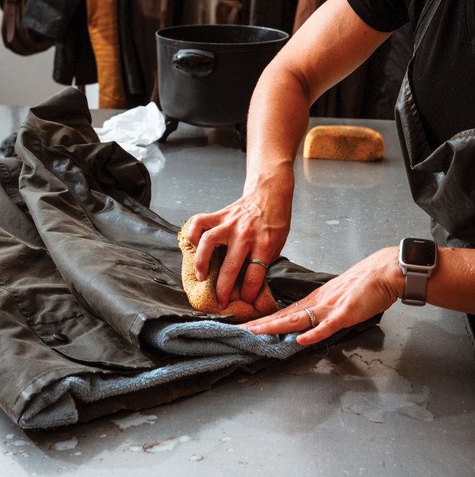a woman cleaning a jacket with a sponge