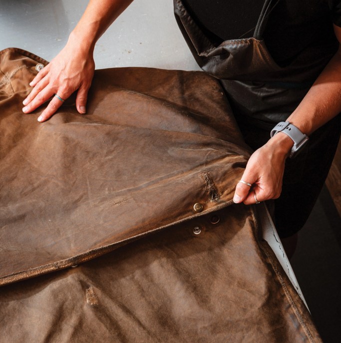 a woman laying out a jacket on a table