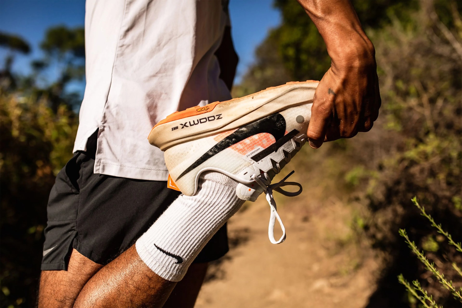 a man holding a shoe on a dirt trail