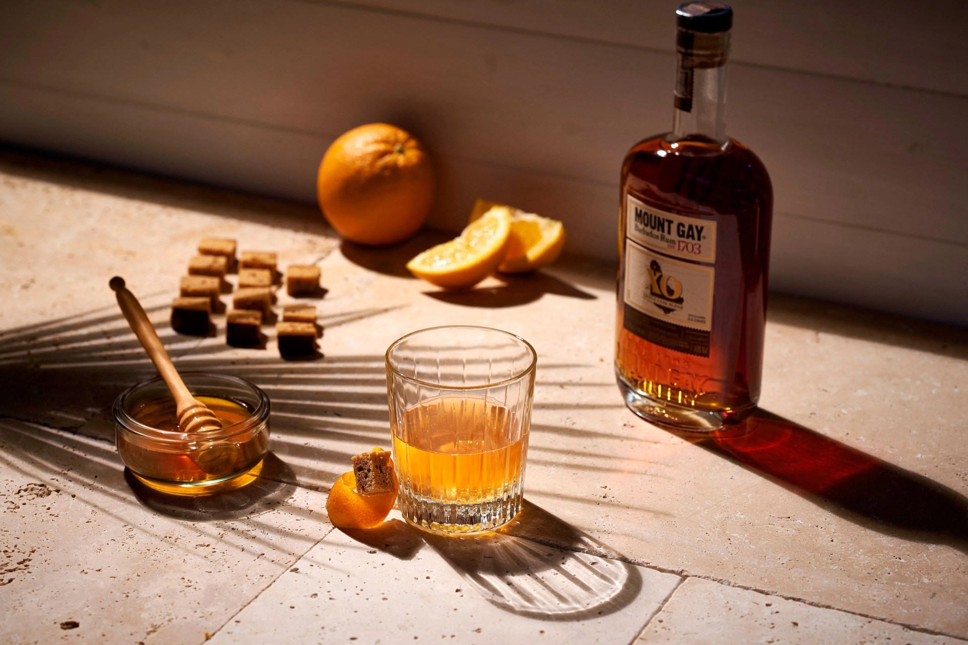 mount gay rum xo next to a mixed drink and honey