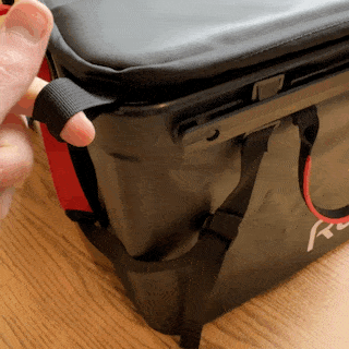 a hand pulling the rux 70l's corner pull tab to seal the lid shut