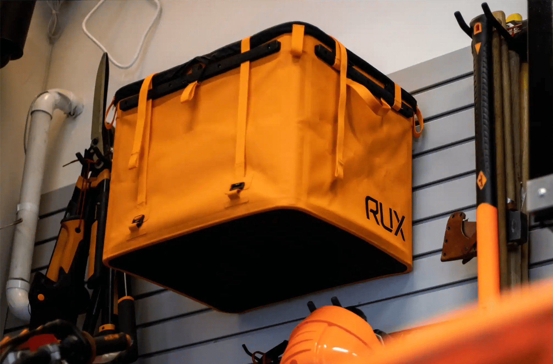 an orange rux 70l hands on a slatwall storage system