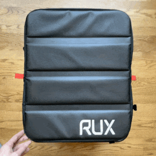 the lid of a black rectangular soft sided storage bin is partially peeled back to reveal its contents