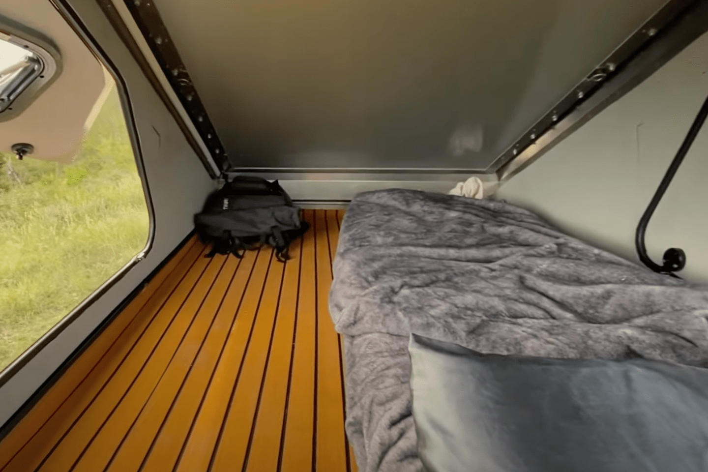 camping trailer sleeping compartment with single bed and backpack