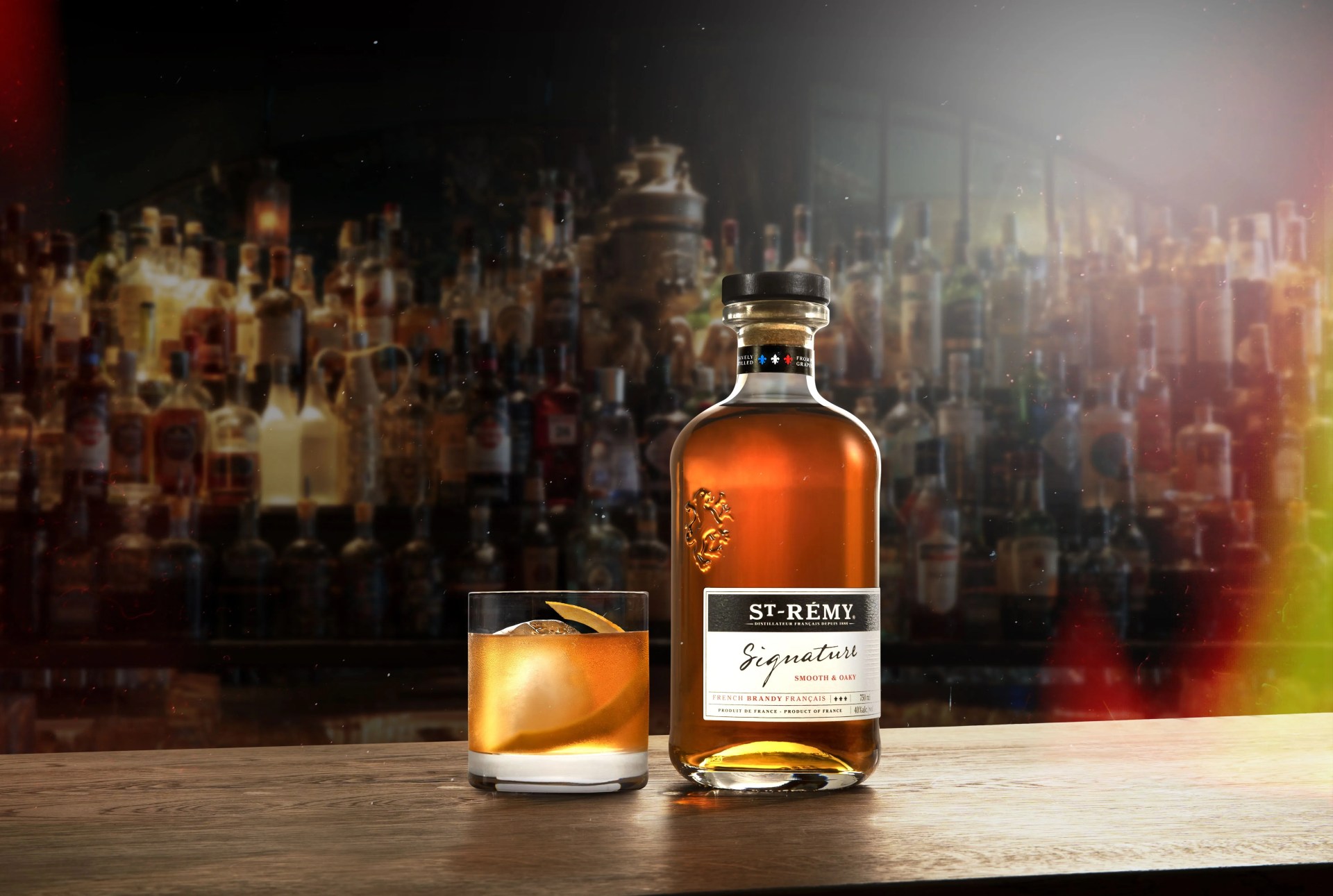 st remy signature brandy on a bar next to an old fashioned
