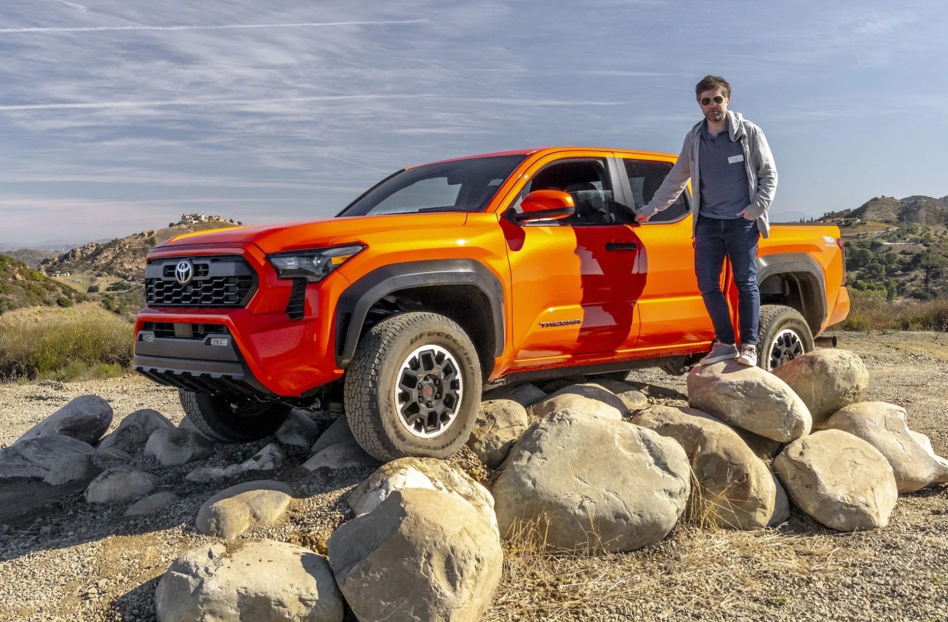 writer standing next to toyota tacoma perched on rocks