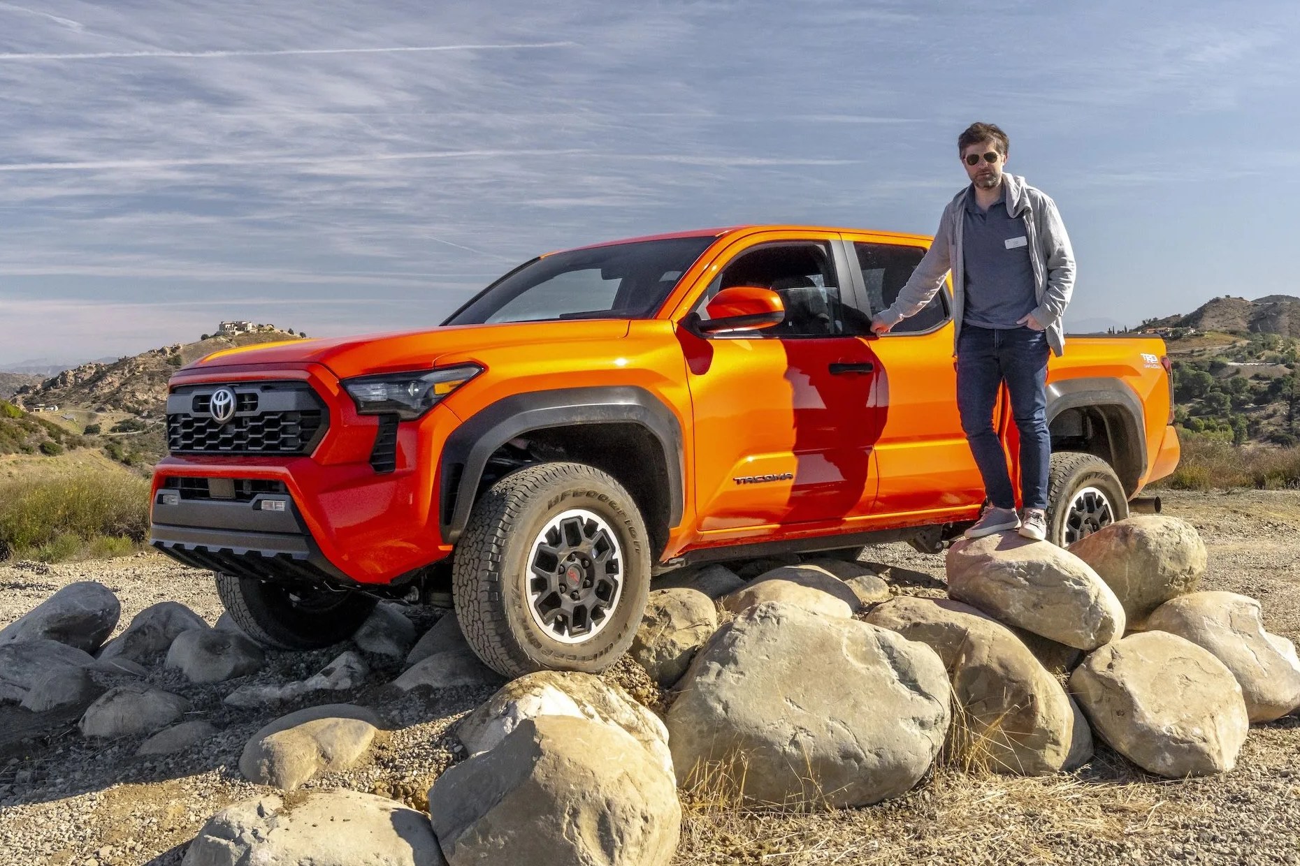 writer standing next to toyota tacoma perched on rocks