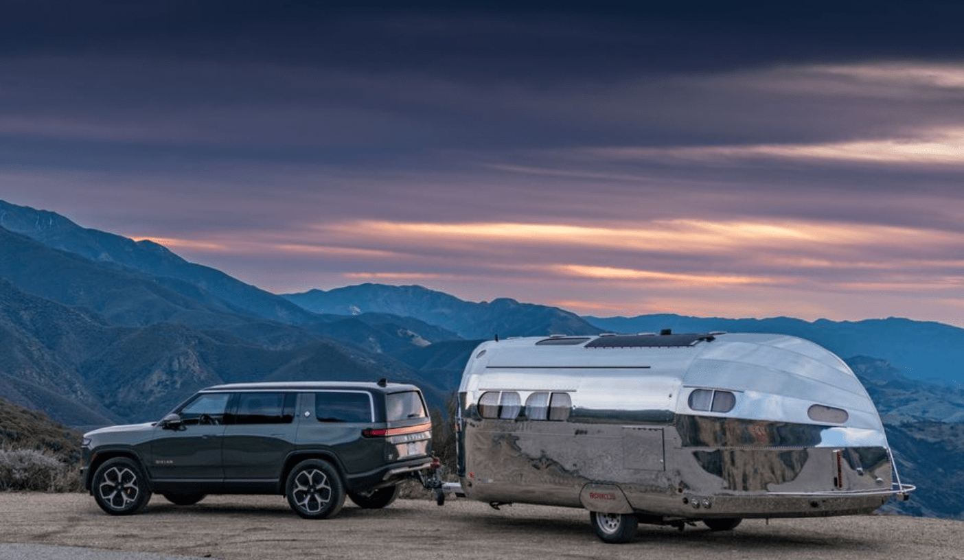 a car and a van parked on a road with mountains in the background