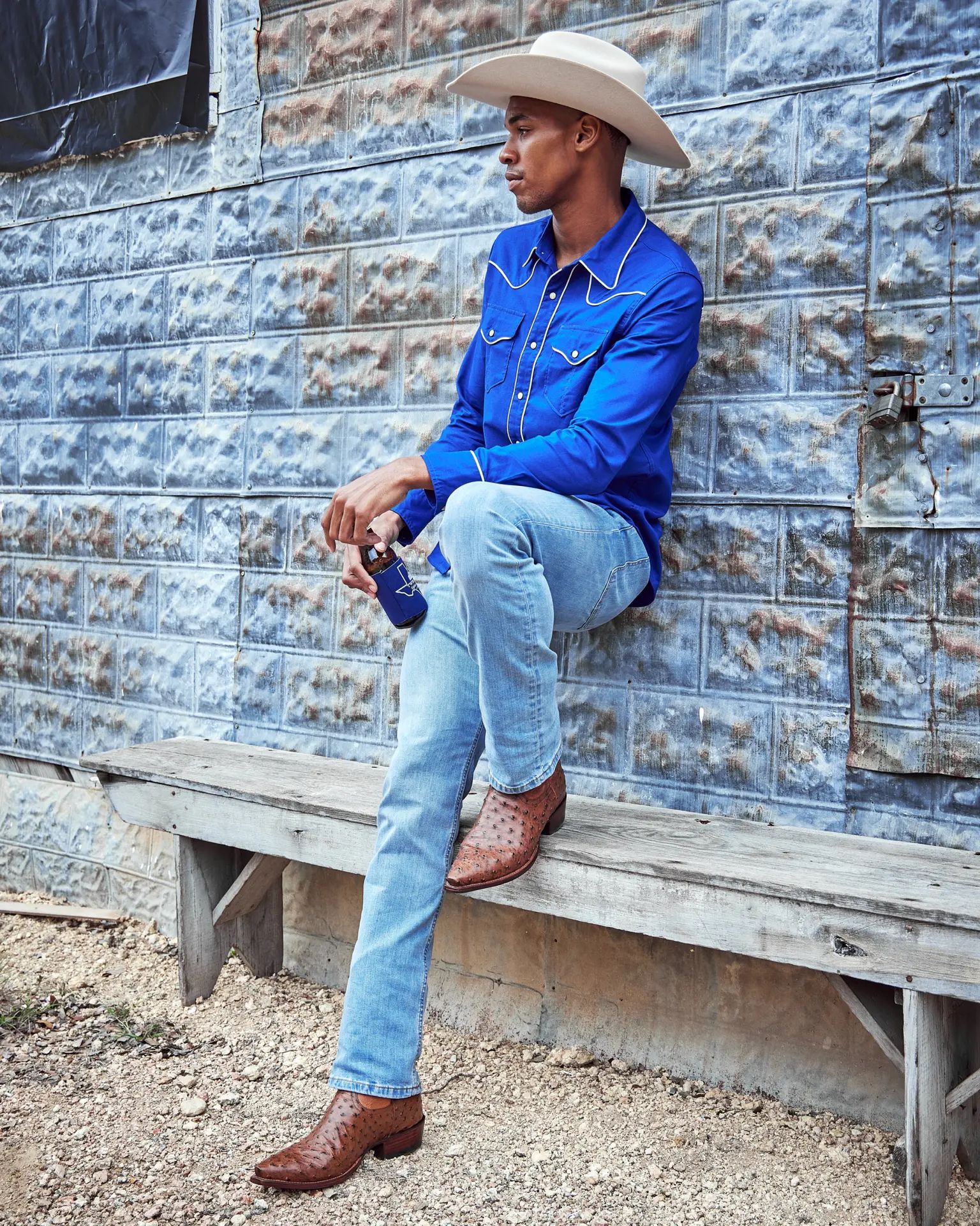 a person leaning on a wall with one leg on a bench wearing tecovas the garrett cowboy boots