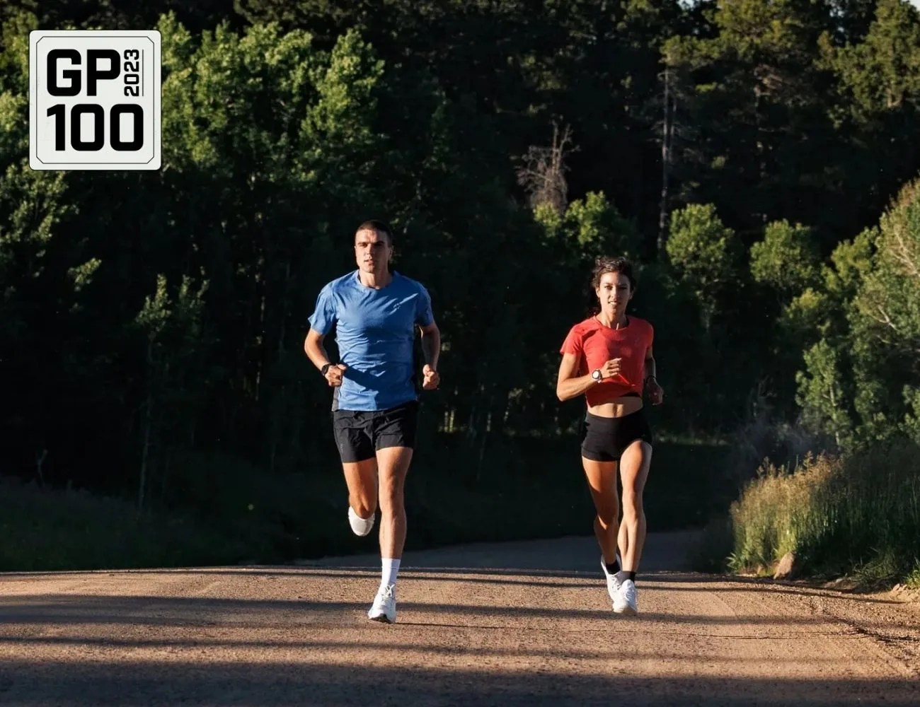 a man and a woman running on a road with trees in the background