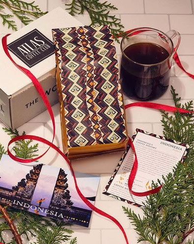 a table with a box, bag of coffee and a cup of coffee on it