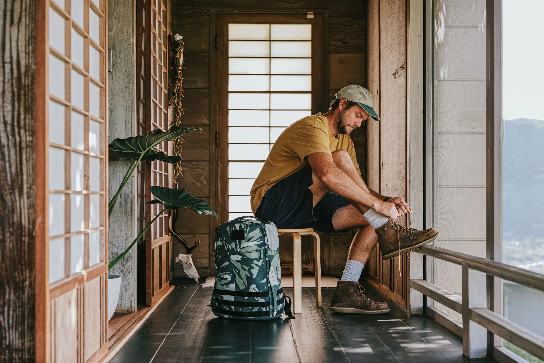 man sitting down tying shoe next to goruck bag