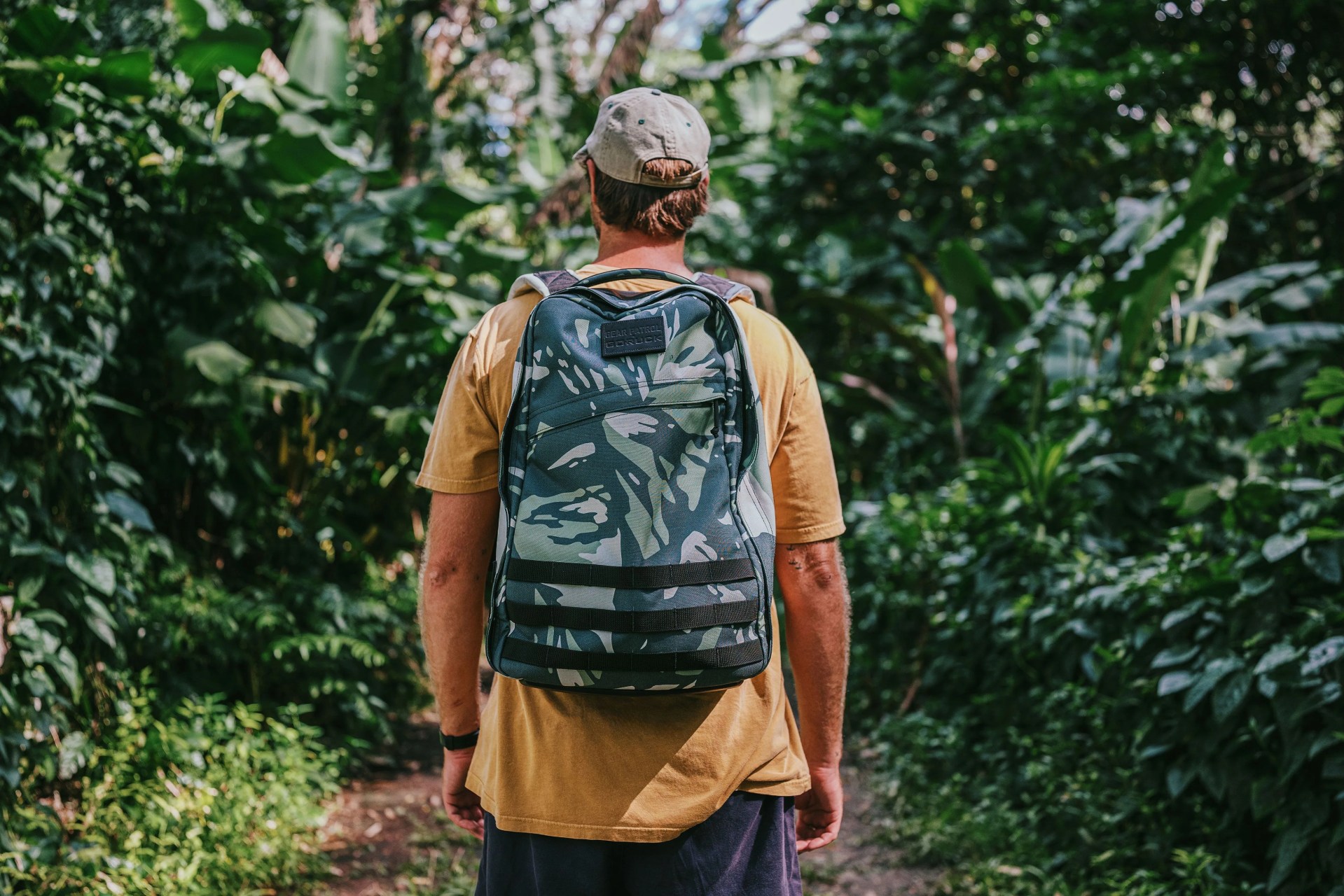 a man walking through forest wearing go ruck back pack