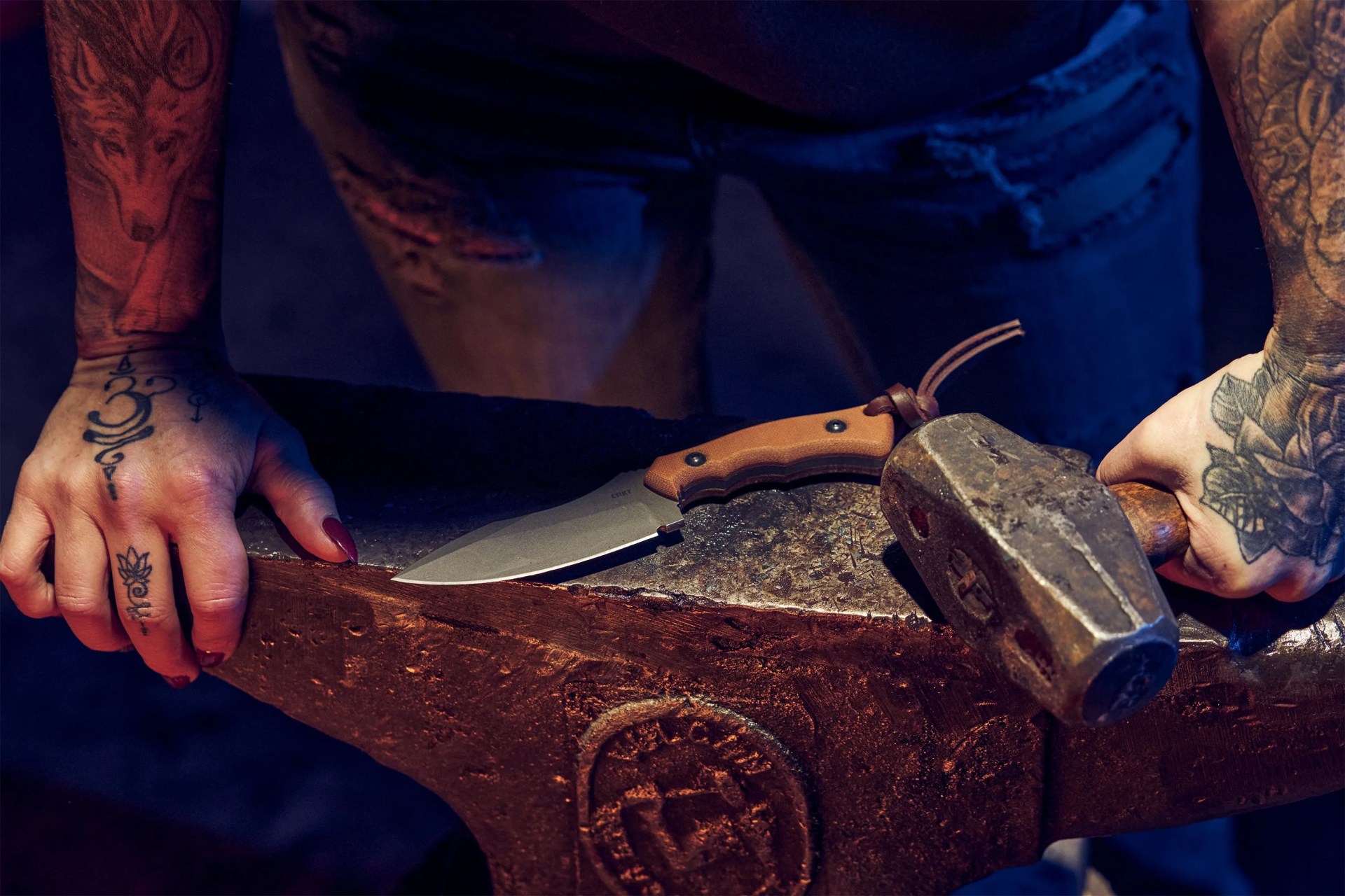 a person standing over a knife on an anvil