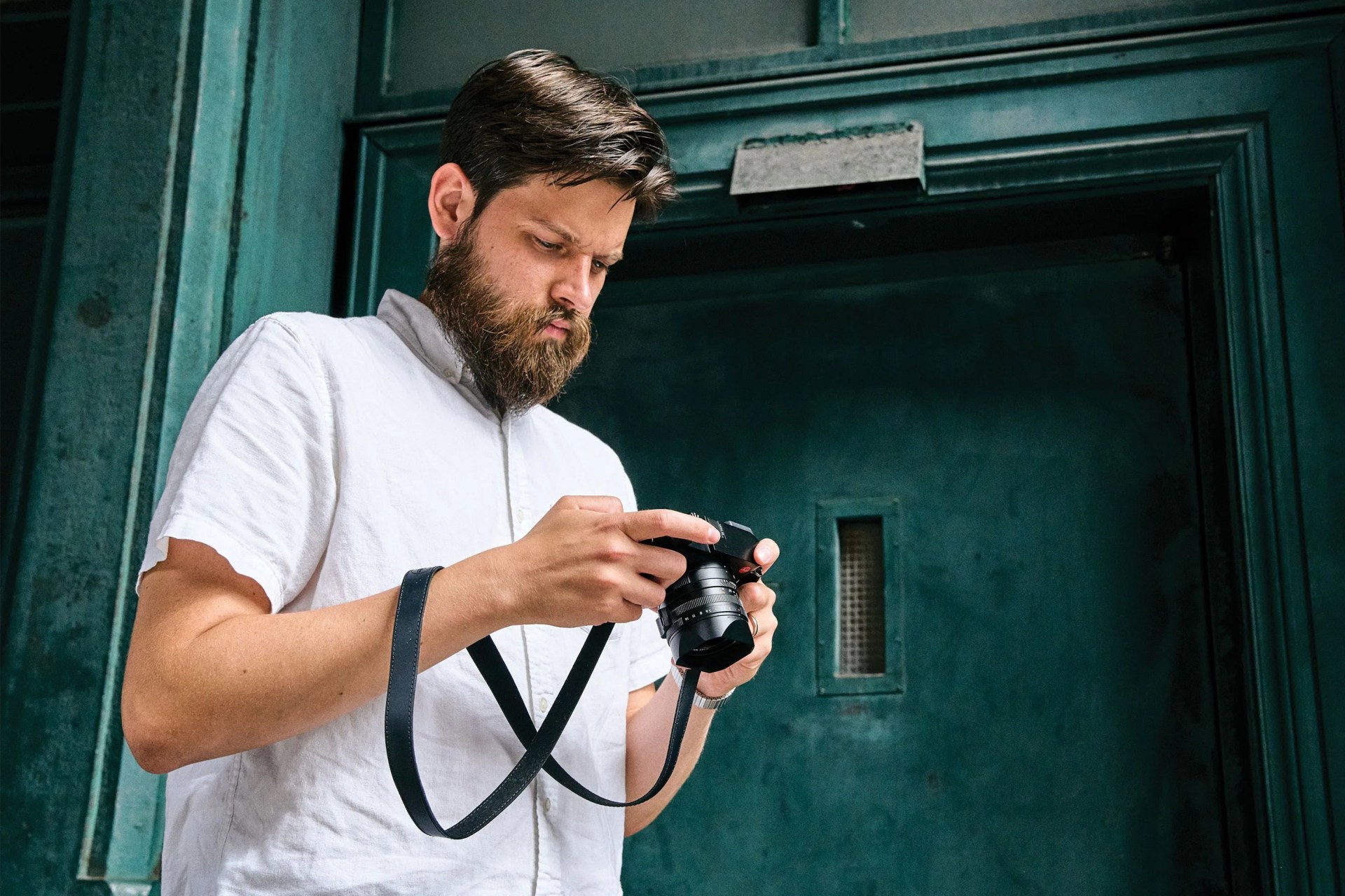 a man looking down at a camera he's holding