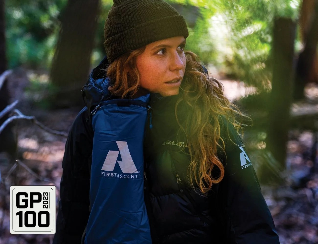 a woman in the woods wearing a jacket and beanie