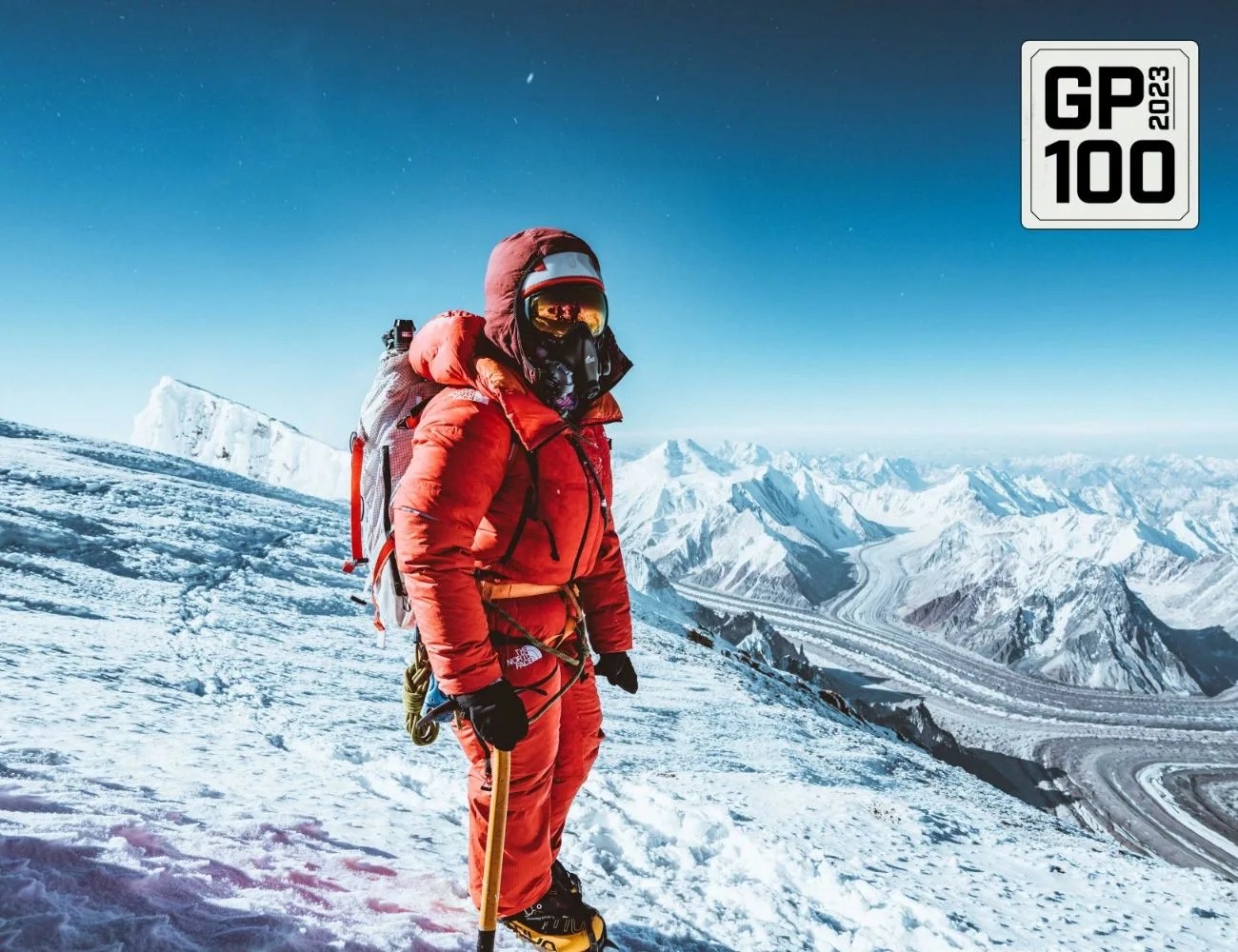 a person wearing a red snow suit and standing on a snowy mountain