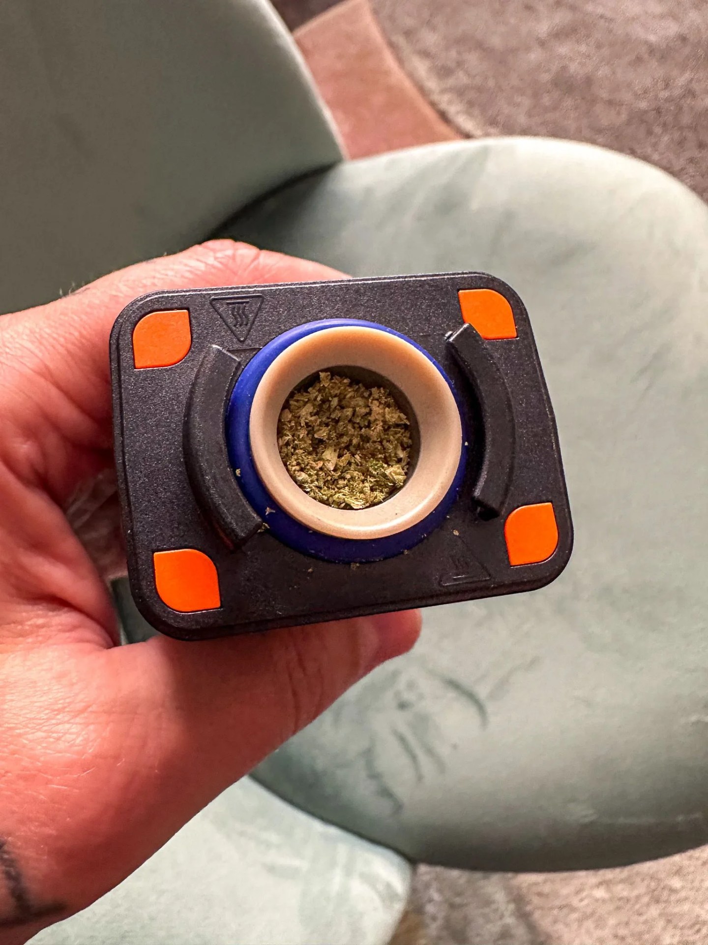 a hand holding a vape with dry weed
