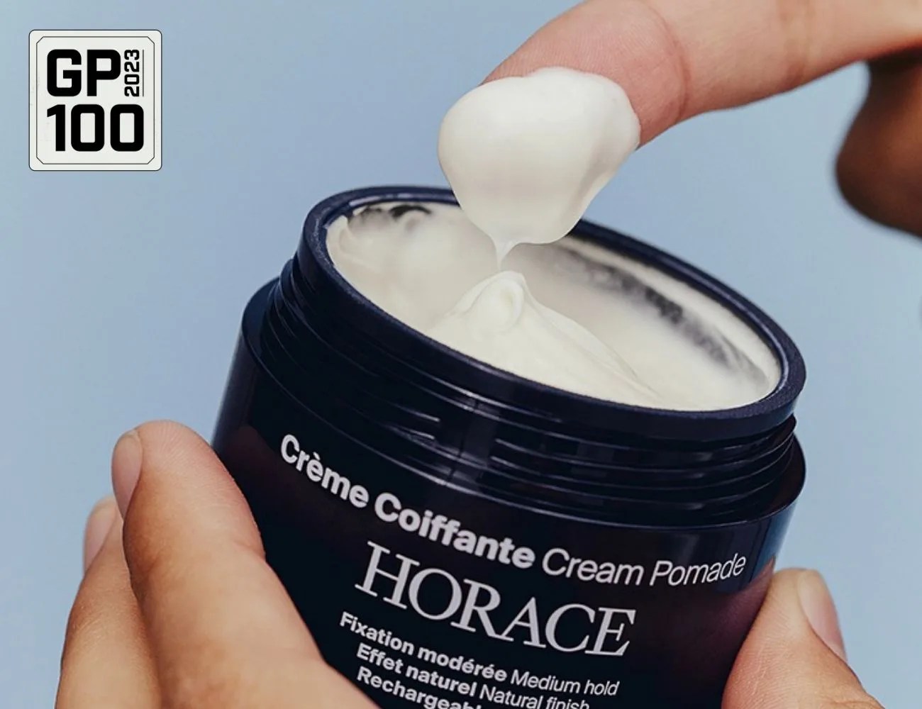 a hand holding a small container of cream